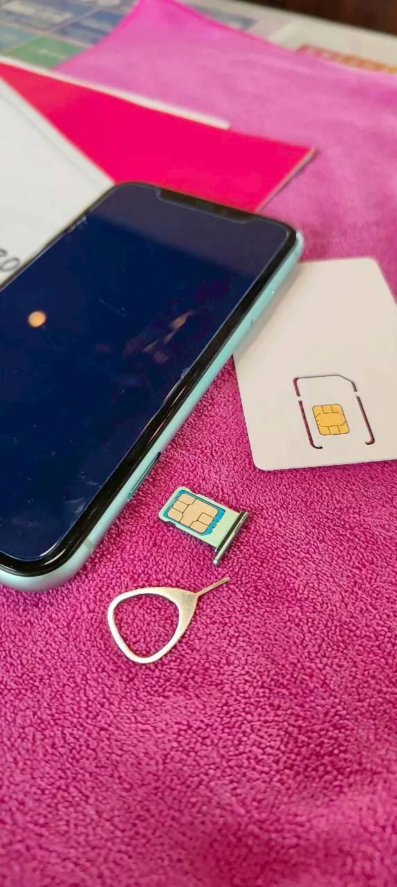 SIMカードの差し替えとイジェクトピンを準備するスマートフォン